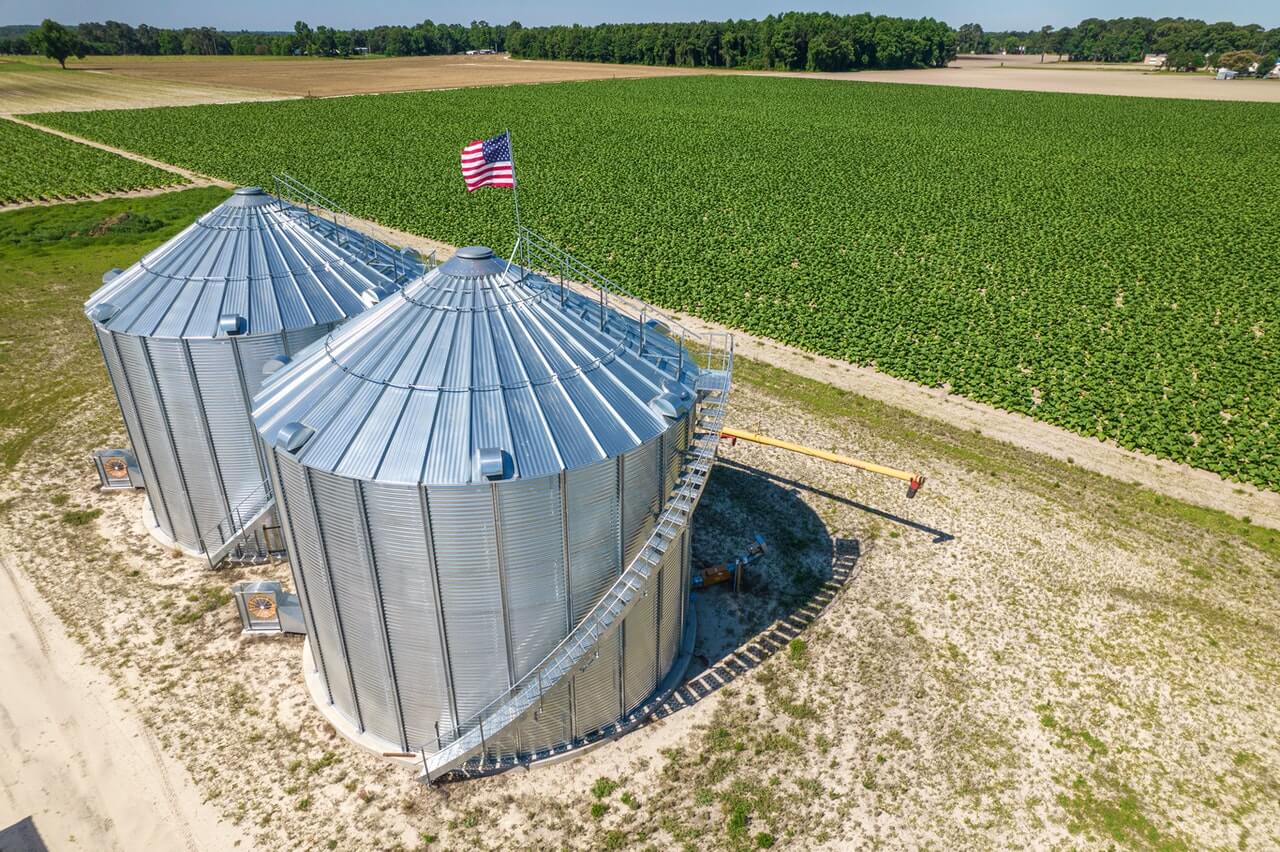 farm silos with field of crops