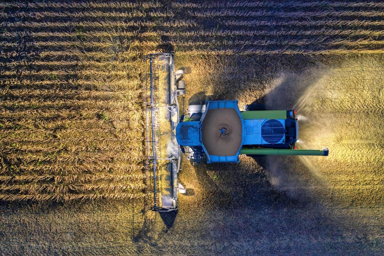 tractor with lights on in a field during harvest