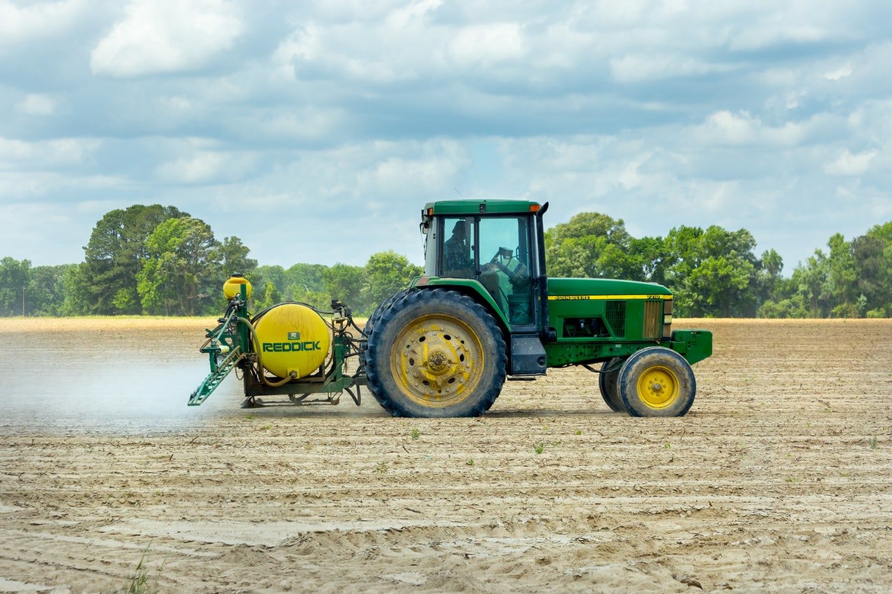 Green tractor being driven by farmer