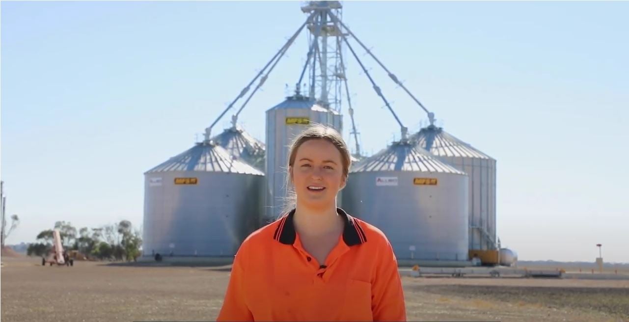 Person standing in front of grain silos